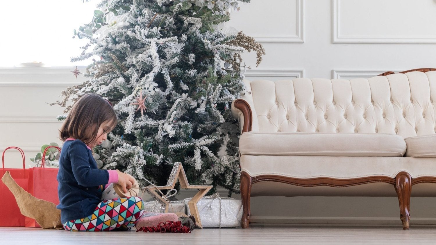 child-opens-gift-under-christmas-tree shades
